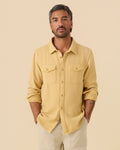 Man wearing a yellow Outerknown Blanket shirt against a beige background